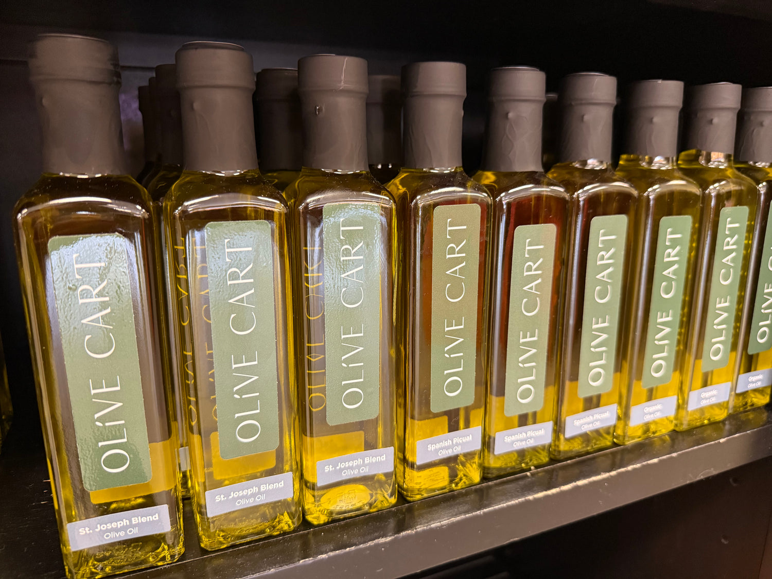 Row of Olive Cart olive oil bottles on a shelf