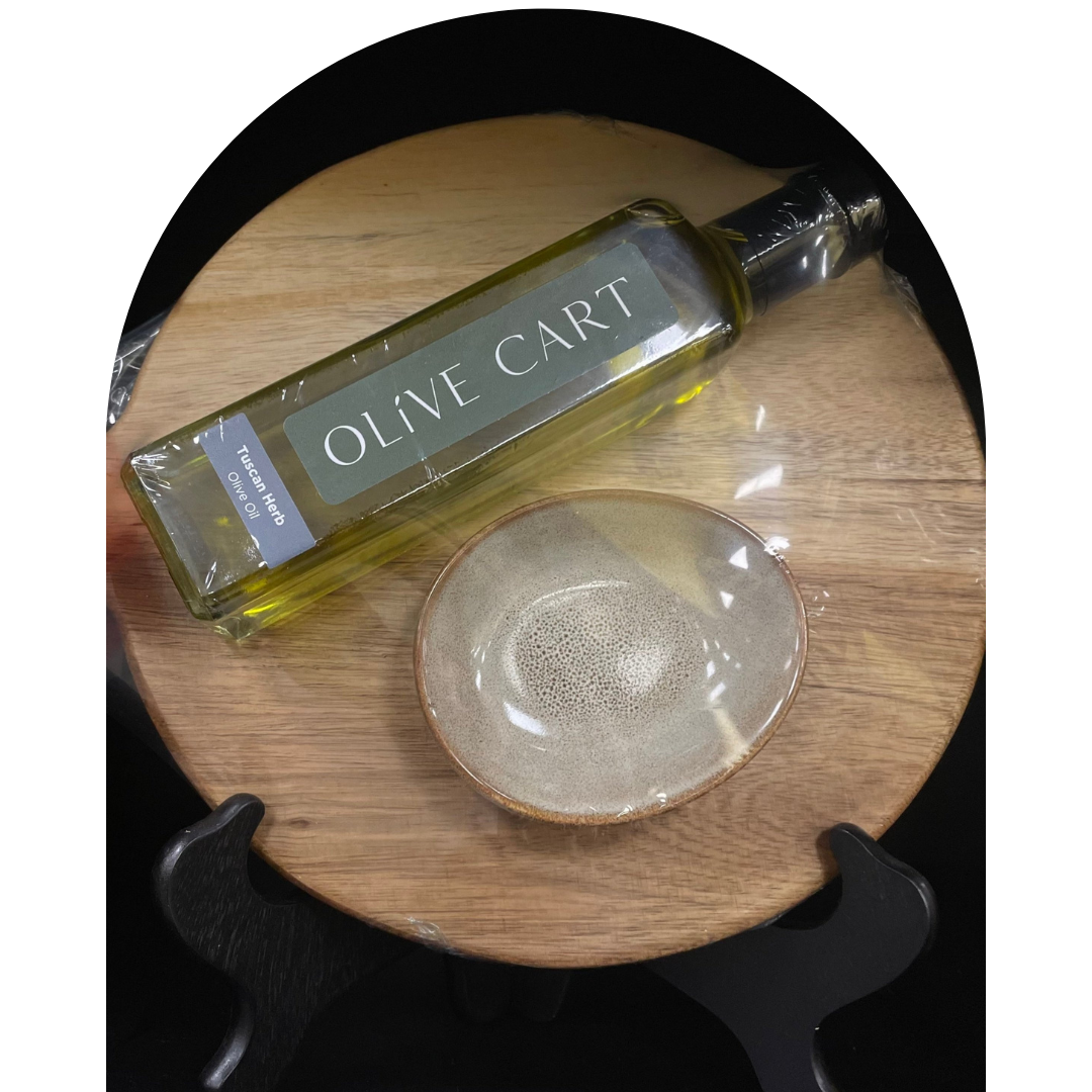 Olive Cart olive oil bottle on a wooden board with a dipping bowl.