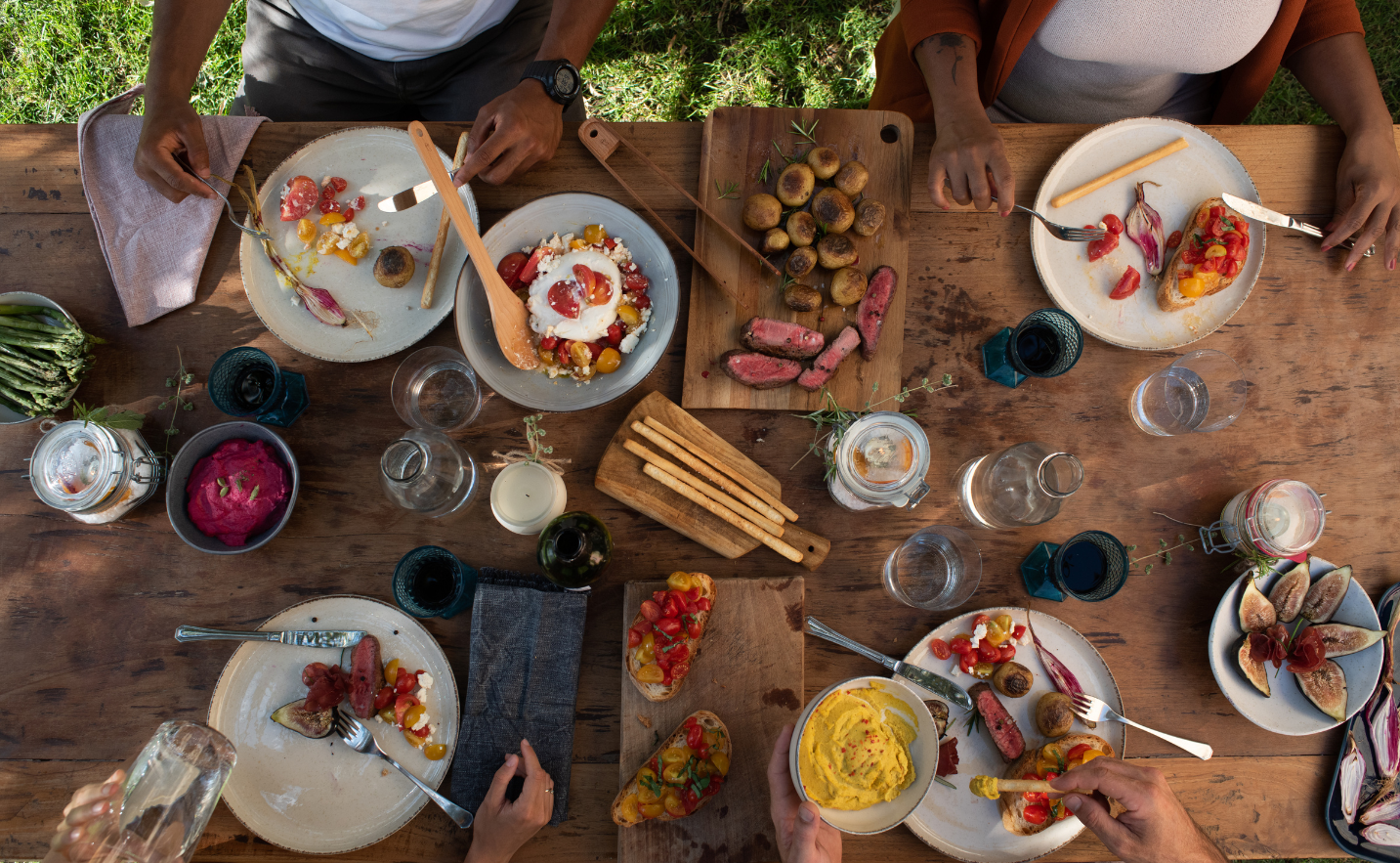 People enjoying a meal together at a wooden table with various dishes.