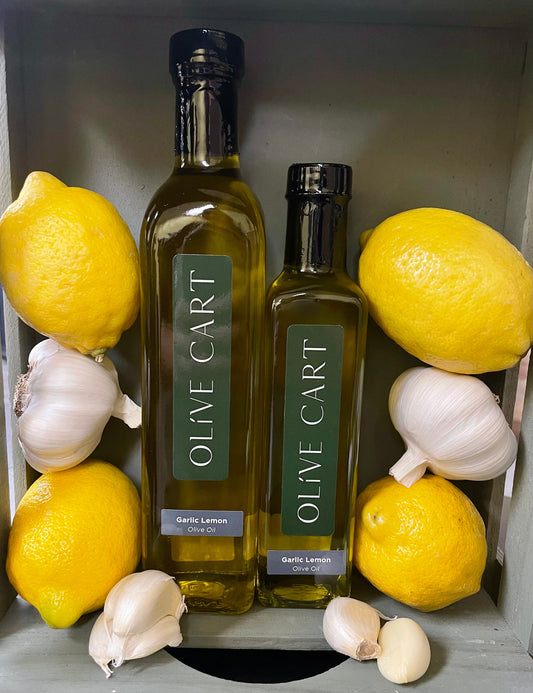 Two bottles of Olive Cart garlic lemon olive oil and lemons and garlic